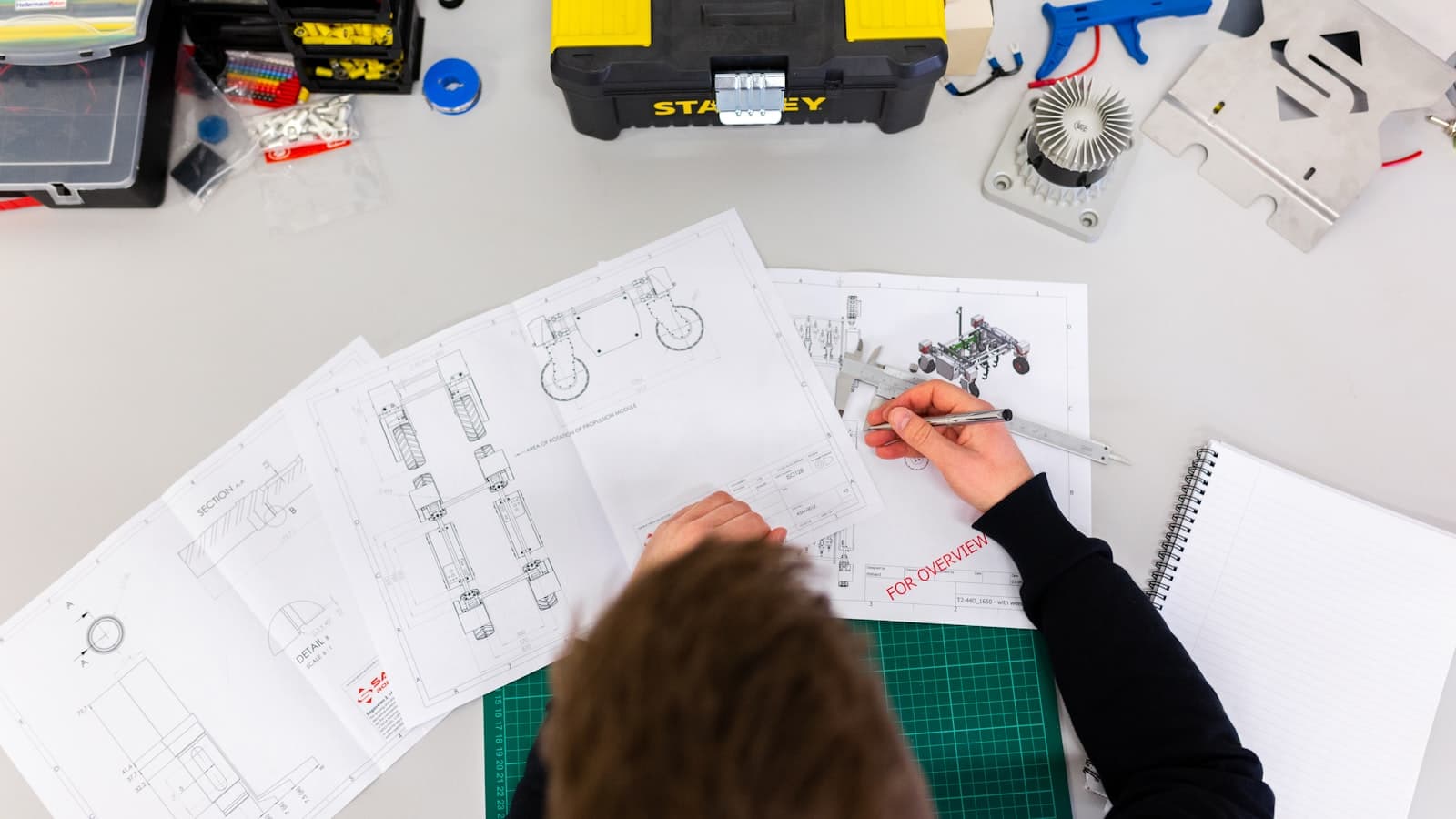 Person reviewing technical notes and tools at a workbench
